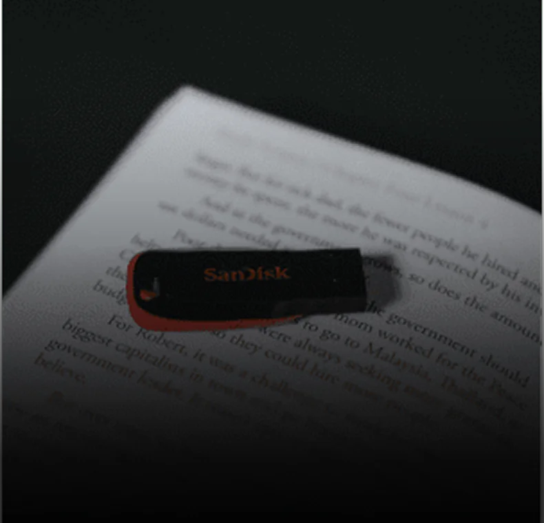 SanDisk USB drive on a book page, symbolic of digital evidence for an unlawful pornography attorney.