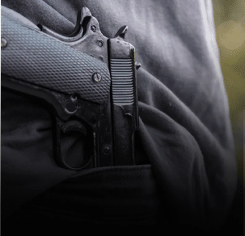 Close-up of handgun tucked into waistband, relevant to weapons charge defense.
