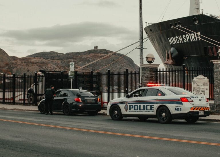 Police car with lights on next to a stopped car, hinting at a traffic ticket.